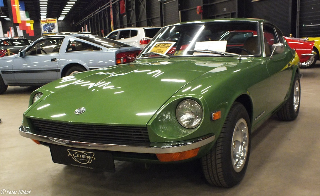 En vackert bevarad grön Datsun 240Z utställd i en inomhusauktionslokal med Albers-märket synligt.